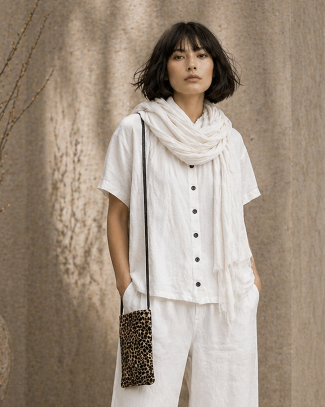 Jen Kahn small leather shoulder bag in giraffe calf skin print leather worn crossbody on model in white linen outfit