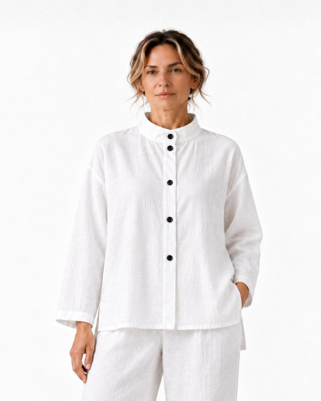 Model wearing the white Jen Kahn High Collar Linen Shirt with white linen pants, showing the high collar, black press-stud fastening and long sleeves.